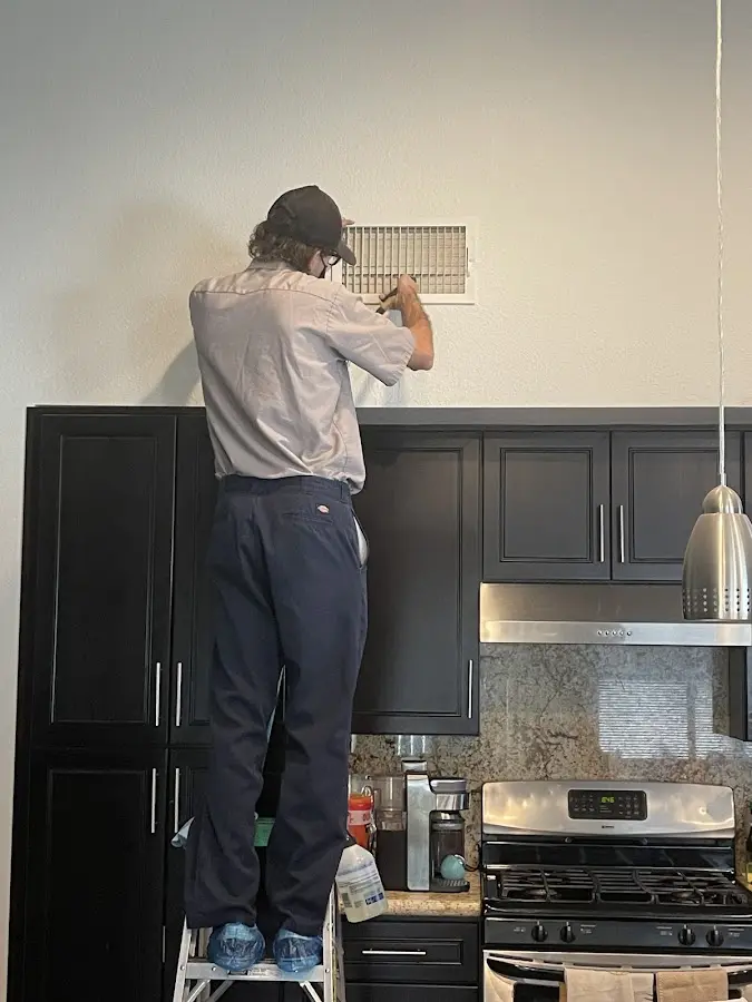 Technician inspecting an air vent during HVAC service in Greenfield